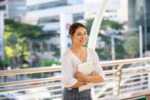 Portrait of young beautiful business woman at outside. Crossed arms