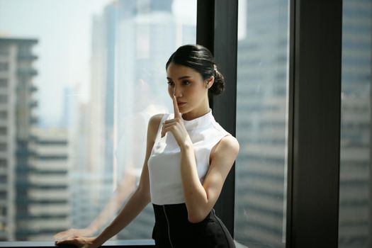 Portrait of confident businesswomen in office looking away by window