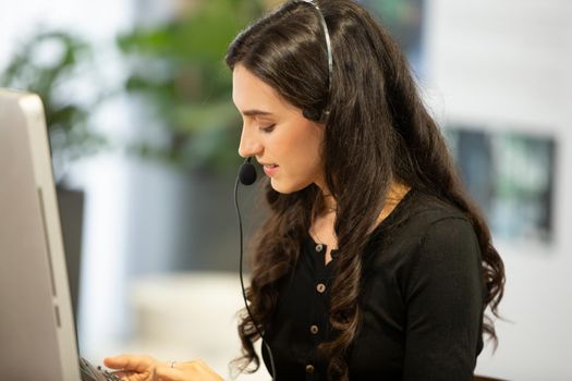 side view.the call center operator and her colleagues work in the office.