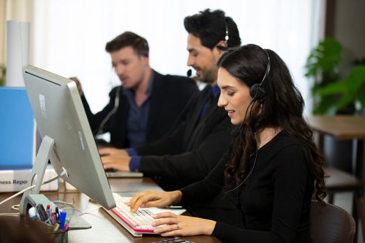 Smiling customer support operator with hands-free headset working in the office.