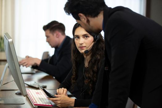 Smiling customer support operator with hands-free headset working in the office.