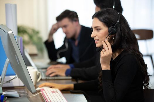 side view.the call center operator and her colleagues work in the office.