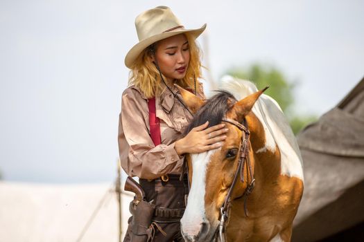 Cowgirl standing by horse at outdoor.