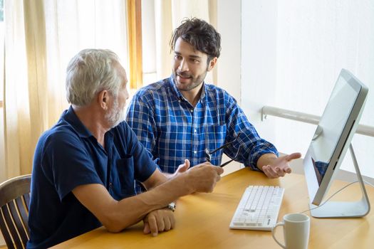 man teaching elderly man to using computer