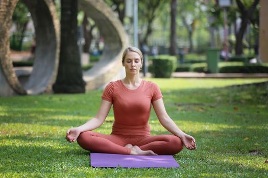 Young attractive smiling woman practicing yoga pose, working out, wearing sportswear pants, bra, full length, outdoor.