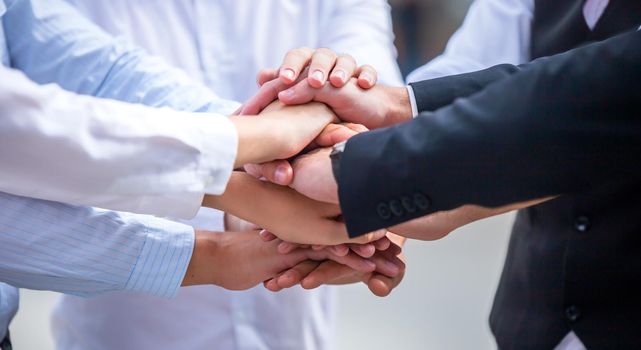 Stack of hands. Unity and teamwork concept. Close up top view of young business people putting their hands together