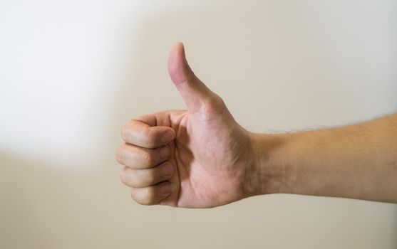 Close up of thumb up against white background.