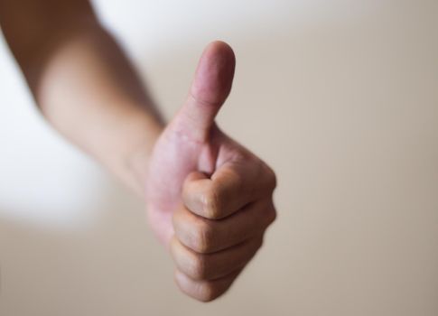 Close up of thumb up against white background.