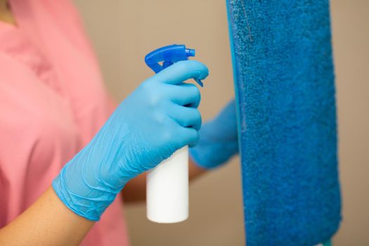 Close-up women hand in a blue rubber glove and cleaning spong in the picture, removes and washes bathroom sink and mirror.