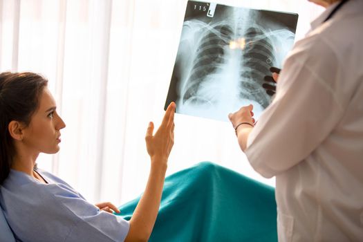 Doctor explaining lungs x-ray to women patient in clinic or Doctor in the office examining an x-ray and discussing with a patient