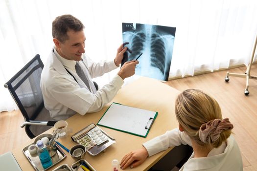 Doctor explaining lungs x-ray to women patient in clinic or Doctor in the office examining an x-ray and discussing with a patient