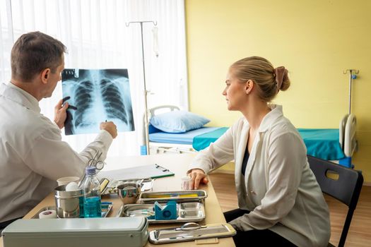 Doctor explaining lungs x-ray to women patient in clinic or Doctor in the office examining an x-ray and discussing with a patient