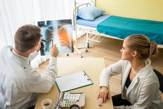 Doctor explaining lungs x-ray to women patient in clinic or Doctor in the office examining an x-ray and discussing with a patient