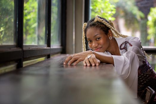 portrait of young african woman showing long braided hair next to face at urban street.