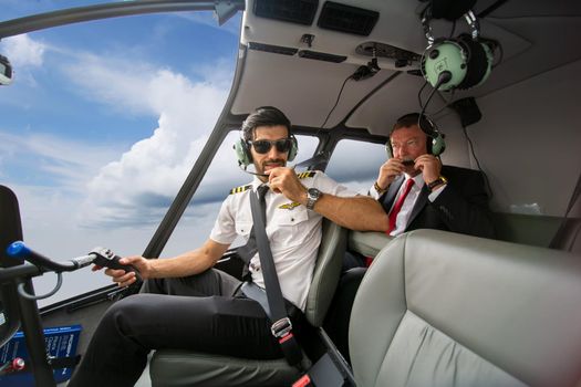 Business people traveling by helicopter , Shot of a mature businessman using a headset while traveling in a helicopter