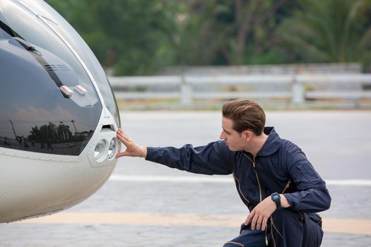 Commercial man pilot in technician suit standing in front of helicopter after check and maintenance engine	