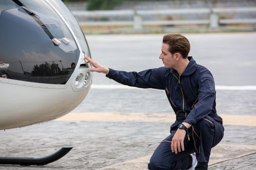 Commercial man pilot in technician suit standing in front of helicopter after check and maintenance engine	