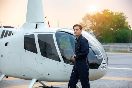 Commercial man pilot in technician suit standing in front of helicopter after check and maintenance engine	