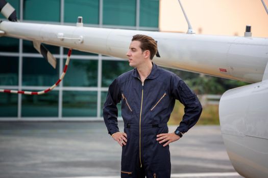 Commercial man pilot in technician suit standing in front of helicopter after check and maintenance engine	