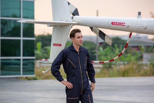Commercial man pilot in technician suit standing in front of helicopter after check and maintenance engine	