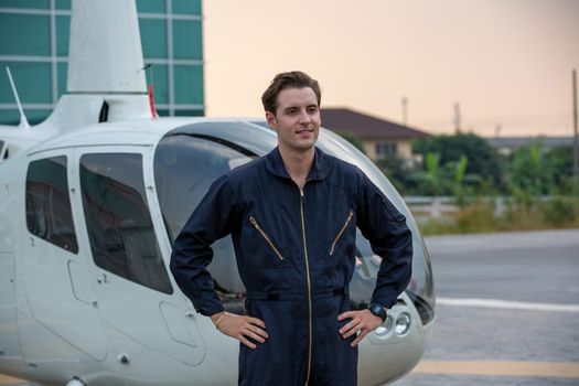 Commercial man pilot in technician suit standing in front of helicopter after check and maintenance engine	