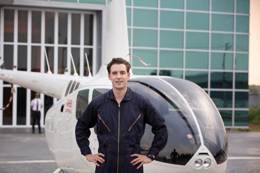 Commercial man pilot in technician suit standing in front of helicopter after check and maintenance engine	