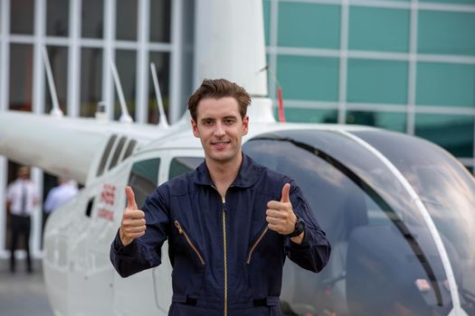 Commercial man pilot in technician suit standing in front of helicopter after check and maintenance engine	