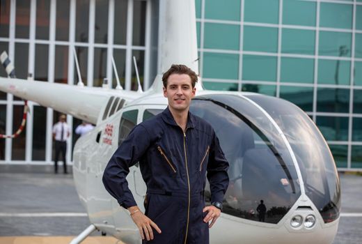 Commercial man pilot in technician suit standing in front of helicopter after check and maintenance engine	