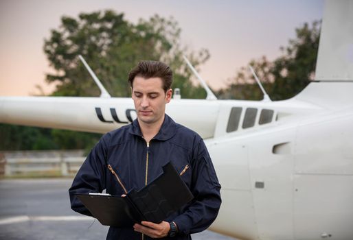 Commercial man pilot in technician suit standing in front of helicopter after check and maintenance engine	