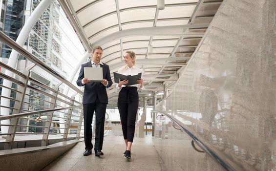 Businessman and businesswoman discussing work while walking outside office