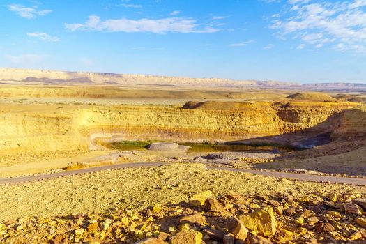 View of a water hole and layered rock formation, along the Ramon Colors Route, in Makhtesh Ramon (Ramon Crater), the Negev desert, southern Israel