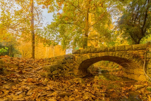 View of the Kesalon Stream with a stone bridge, Crusader farmhouse, trees, and fall foliage, in En Hemed National Park (Aqua Bella), west of Jerusalem, Israel