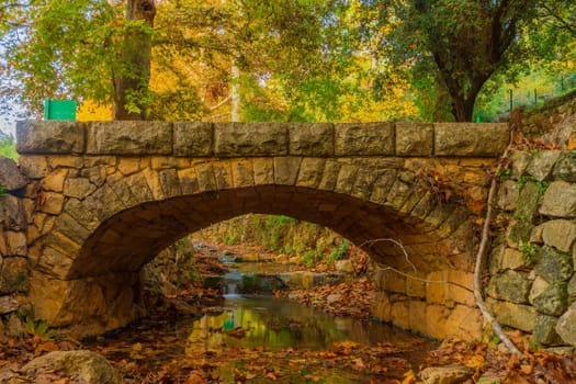 View of the Kesalon Stream with a stone bridge, trees, and fall foliage, in En Hemed National Park (Aqua Bella), west of Jerusalem, Israel