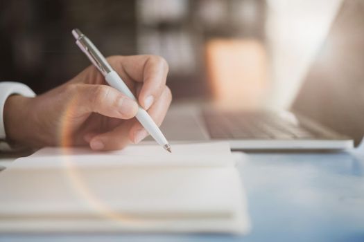 Woman hand writing down in small white memo notebook for take a note not to forget or to do list plan for future.