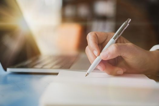 Woman hand writing down in small white memo notebook for take a note not to forget or to do list plan for future.