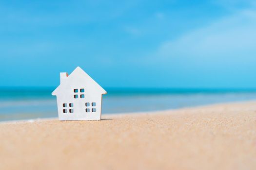 Closed up tiny home models on sand with sunlight and beach background.