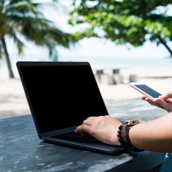 Woman using laptop and smartphone to work study in vacation cady at beach background. Business, financial, trade stock maket and social network concept.