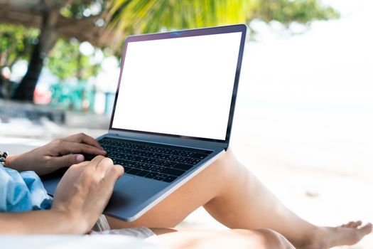 Woman using laptop with white screen background to work study on vacation days at beach background. Business, financial, trade stock maket and social network concept.