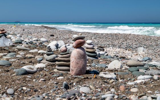 Gravel / pebble beach at the southwest coast of Rhodes island near Apolakkia with ocean water in different blue and turquoise colors and small stone figures
