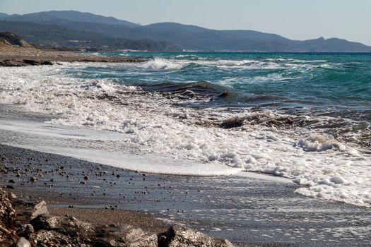 Panoramic view at the coastline with pebble beach and water waves on the westside of Greek island Rhodes between Kamiros and Mandriko