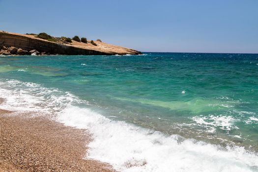 Gravel / pebble beach Akra Fourni nearby Monolithos  at Rhodes island with multi colored ocean water, waves and rocks 