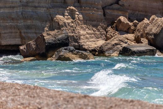 Gravel / pebble beach Akra Fourni nearby Monolithos  at Rhodes island with multi colored ocean water, waves and rocks 
