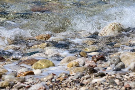 Close-up of ocean water flowing over pebble stones on a beach at Rhodes island, Greece