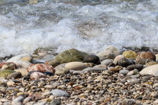 Close-up of ocean water flowing over pebble stones on a beach at Rhodes island, Greece