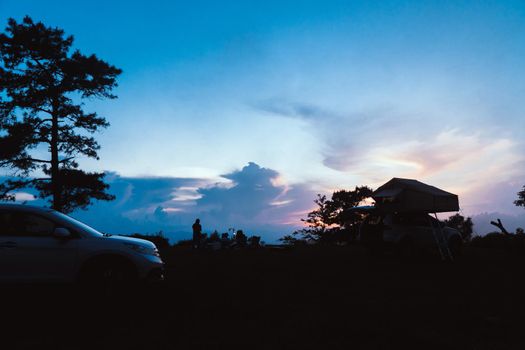 People are camping at the top of the hill at sunset