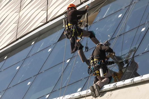 Zaragoza, Spain - Sep. 30, 2020: Specialist technical workers carry out maintenance and rehabilitation work, wearing safety harnesses, on the facade of the Zaragoza bridge pavilion.