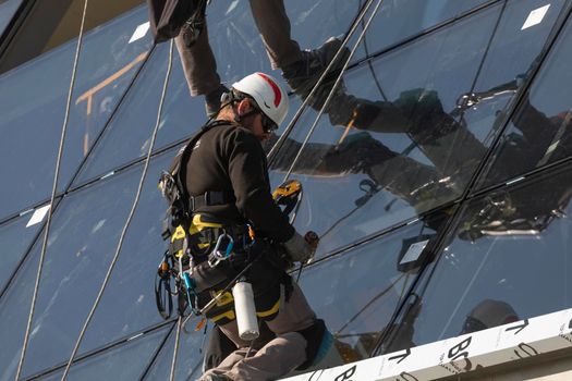 Zaragoza, Spain - Sep. 30, 2020: Specialist technical workers carry out maintenance and rehabilitation work, wearing safety harnesses, on the facade of the Zaragoza bridge pavilion.