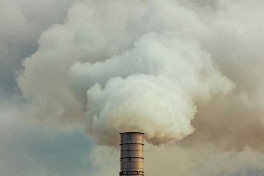 A large manufacturing facility in a regional township with steam coming from the chimney stacks during processing