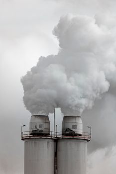 A large manufacturing facility in a regional township with steam coming from the chimney stacks during processing