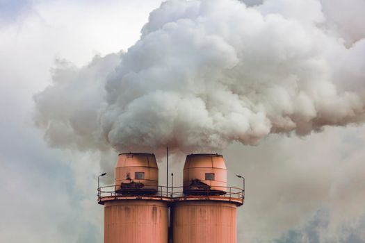 A large manufacturing facility in a regional township with steam coming from the chimney stacks during processing